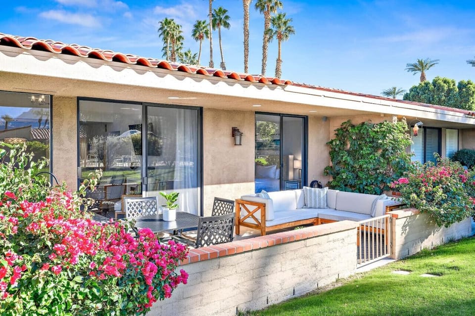 Bask in the sunshine on this lush patio, surrounded by vibrant flowers and swaying palm trees. With cozy seating and serene views, it`s the perfect spot to relax and unwind.