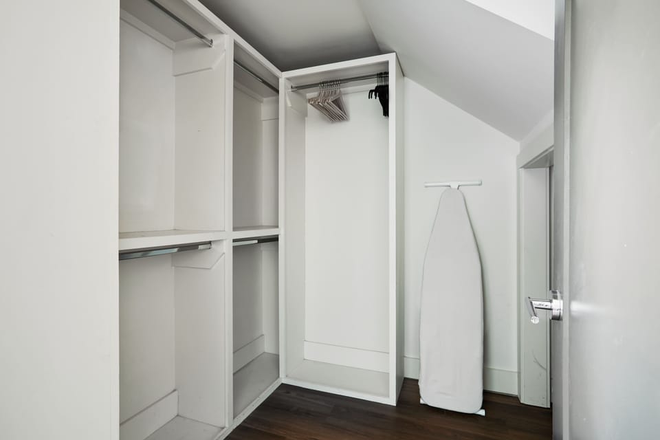 Stay organized with this spacious walk-in closet, complete with ample storage and an ironing station.