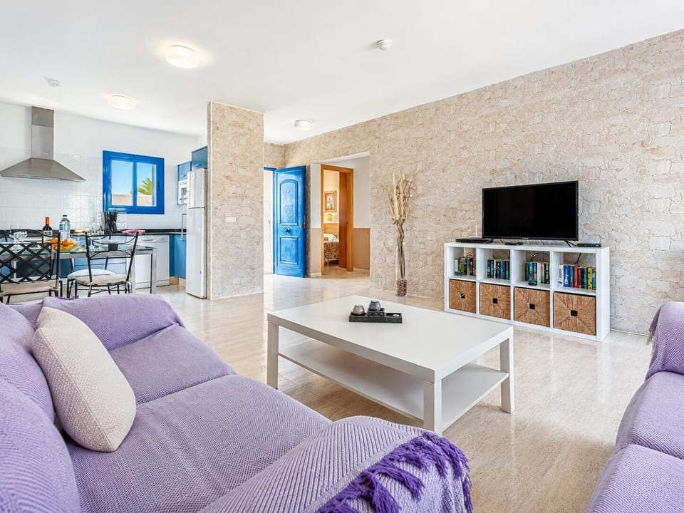 Open-plan living room with sofas, dining area, kitchen, A/C, WiFi internet, satellite TV, and terrace access