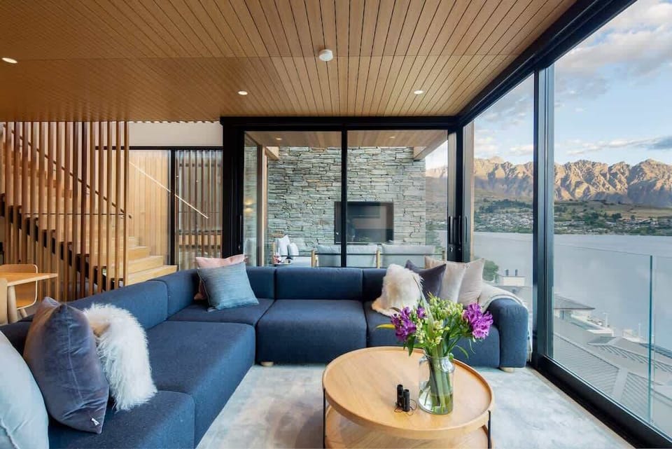 Inviting Living Room with Fireplace and Views – Relax in this beautifully appointed living room, with a crackling fireplace and large windows framing amazing views of the lake and mountains