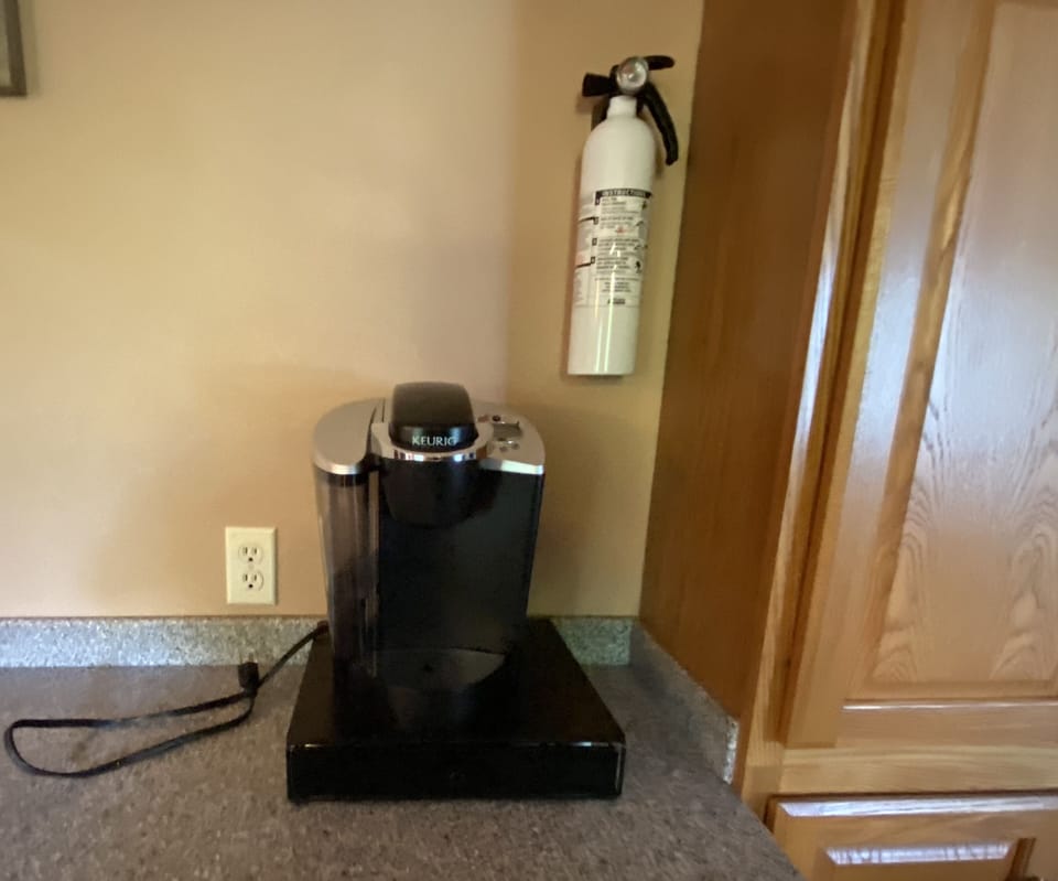 Keurig coffee maker with coffee supplies and fire extinguisher in kitchen.