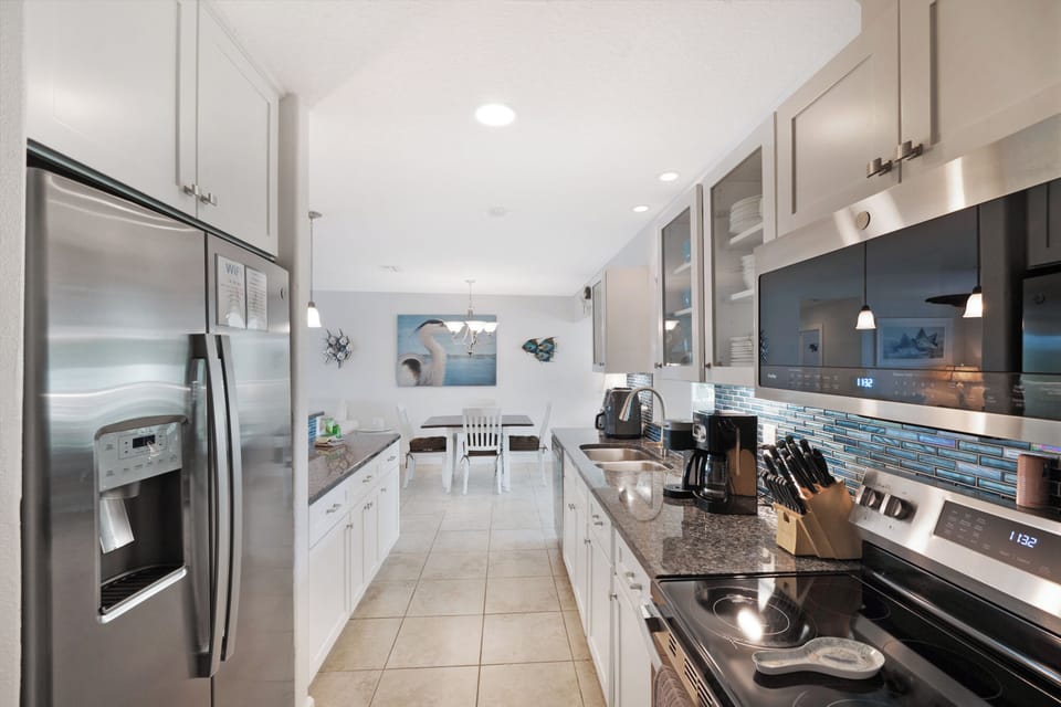 Cook together in your fully equipped kitchen with granite counters, stainless appliances, and ocean-inspired tile backsplash.