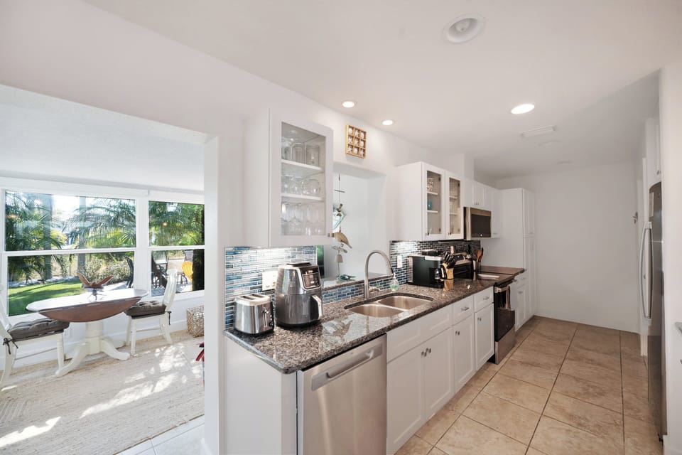 Your modern kitchen awaits with granite counters, stainless appliances, and tropical views through bright windows.