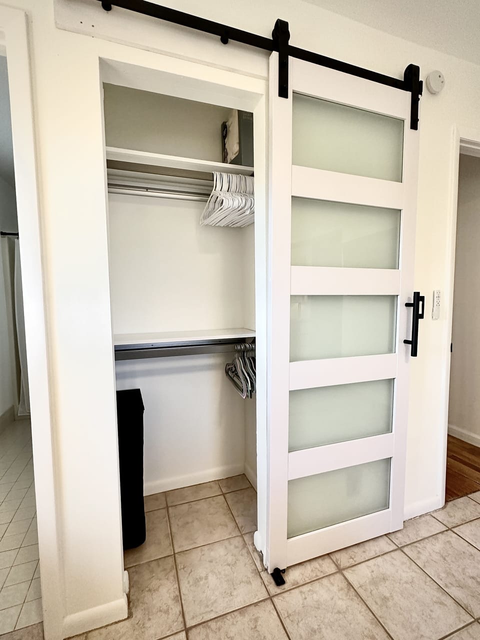 Master closet with sliding glass door and two sections for clothes and shoes.