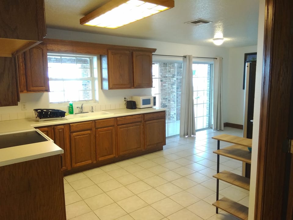 Kitchen in two bedroom apartment with sliding door to outside deck and pool.
