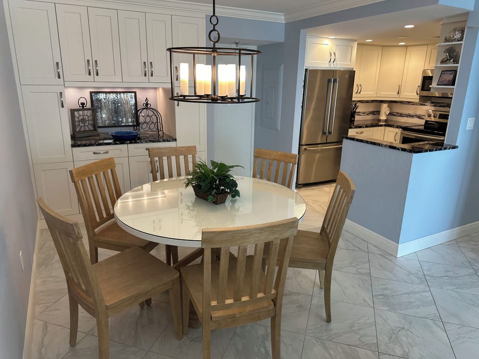 Coastal 54" round dining table, 6 chairs with adjacent dry bar and kitchen.
