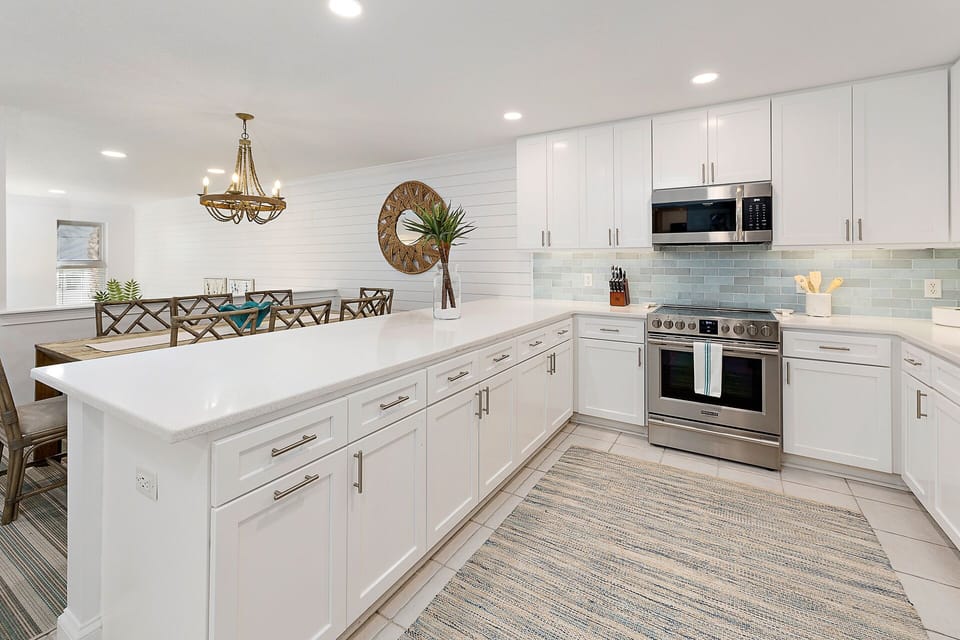 Kitchen features stainless steel appliances and beautiful white countertops.