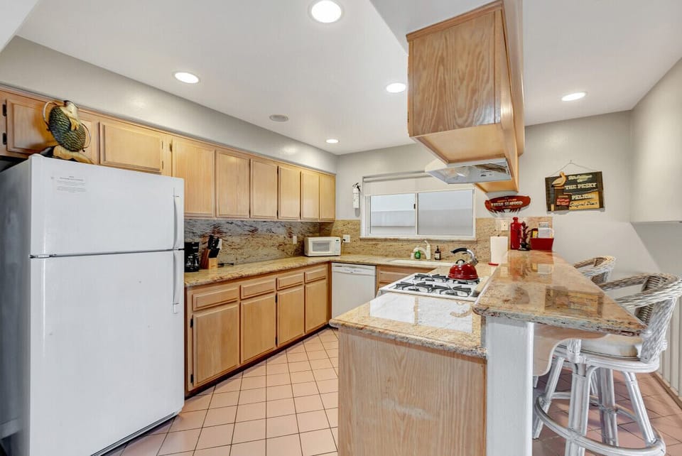 Fully equipped kitchen w/ wood cabinets, full-size fridge & breakfast bar seating