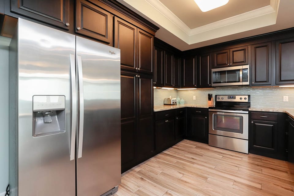 Prepare meals in this stylish kitchen featuring dark cabinetry, stainless appliances, and ample counter space
