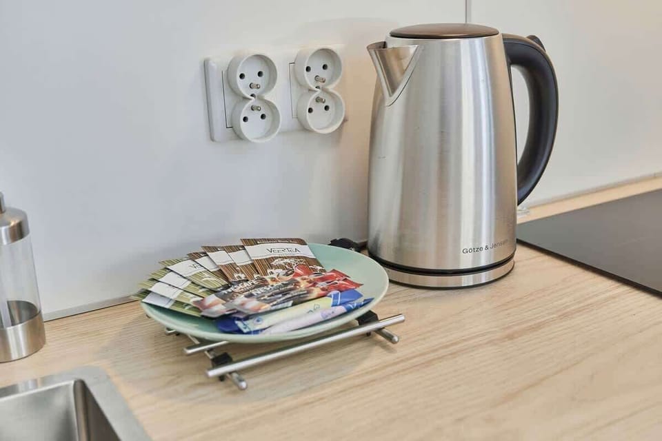 Close-up of a silver electric kettle boko which there is a plate with tea bags.