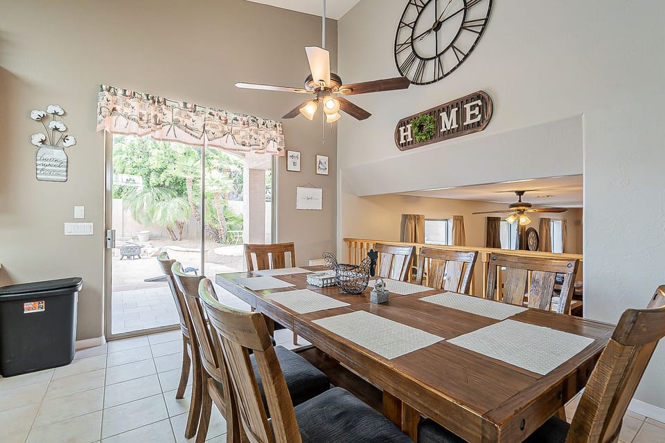 Dining table with ceiling fan and backyard view