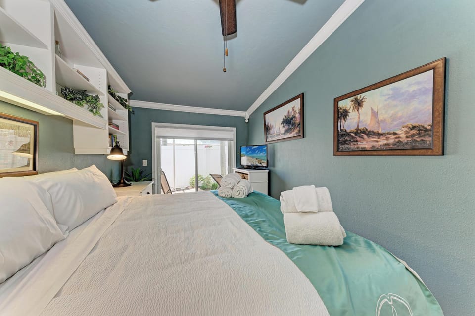 Relax in your coastal-inspired retreat with a plush bed dressed in crisp linens, soothing teal accents, and artwork that brings the desert and palms to life around you.