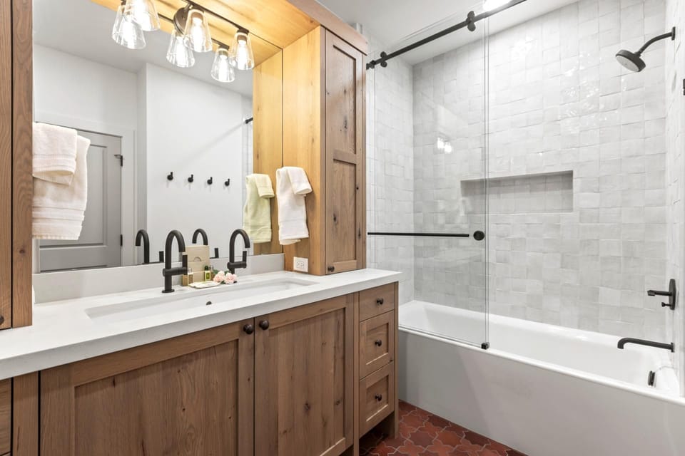 Full bath with shower/tub combo, wood cabinetry, and granite counter connected to the bunk room
