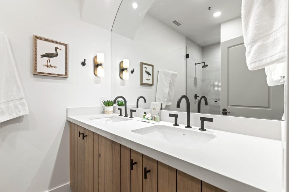 This full bath includes dual sinks, step in shower and sleek fixtures.