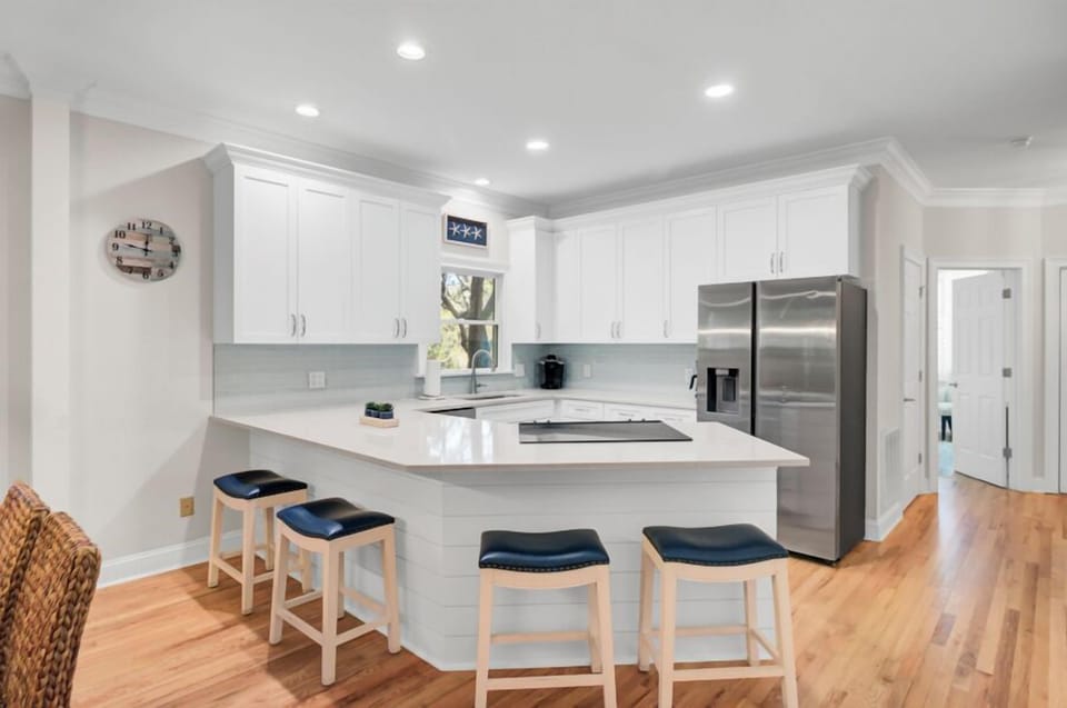 Your modern kitchen awaits with gleaming white cabinets, quartz counters, and a breakfast bar perfect for morning coffee conversations.