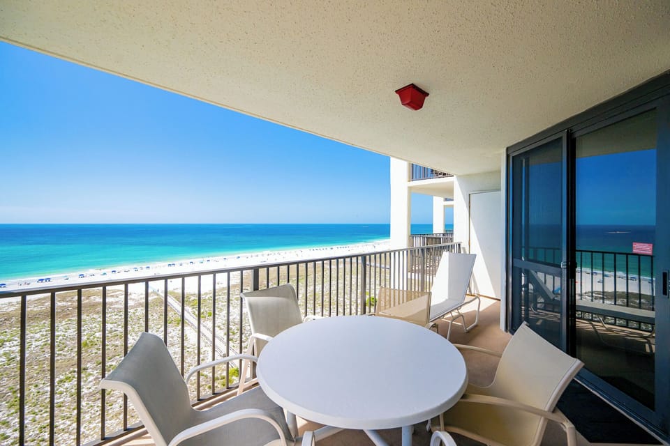 Warm sunlight brightens your balcony where gentle waves create a soothing rhythm on the shore below