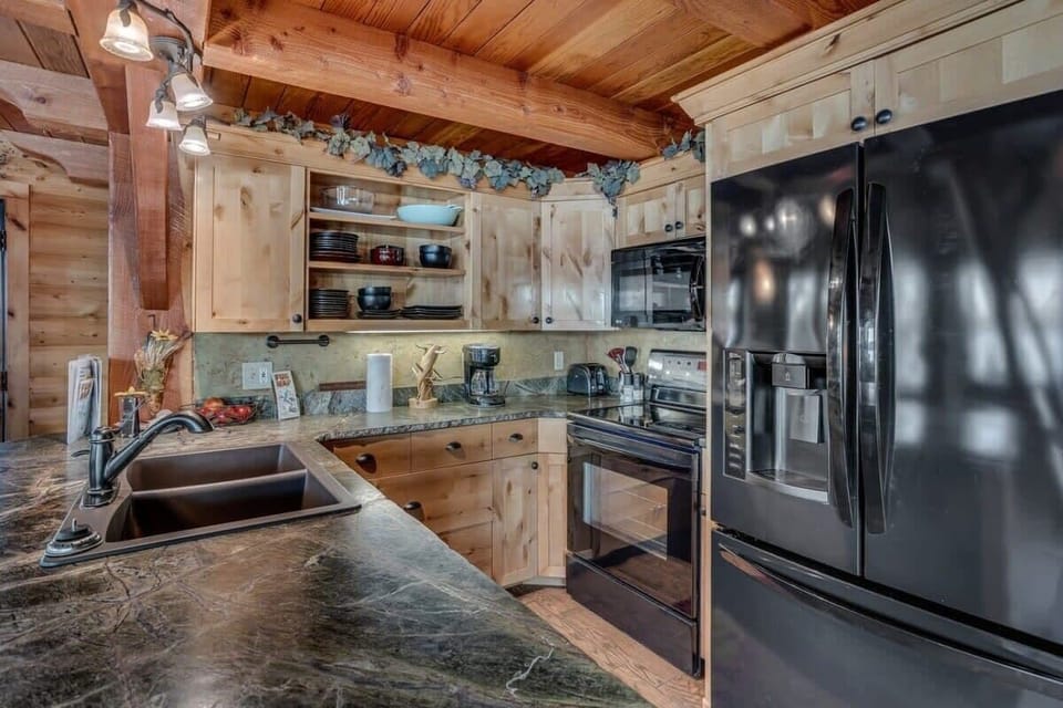 Cook your favorite meals in this rustic kitchen featuring granite counters, stainless appliances, and charming wood beams overhead.