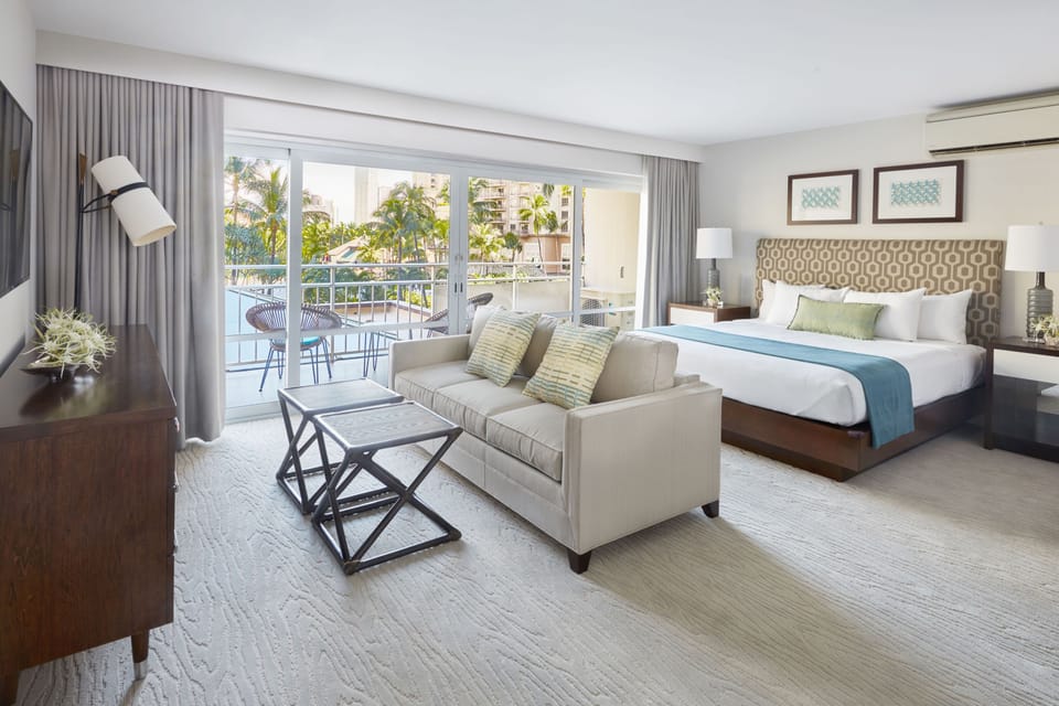Your spacious suite blends rest and relaxation—sink into the plush king bed or lounge on the sofa, then step onto your private balcony with tropical views and waterside scenery.