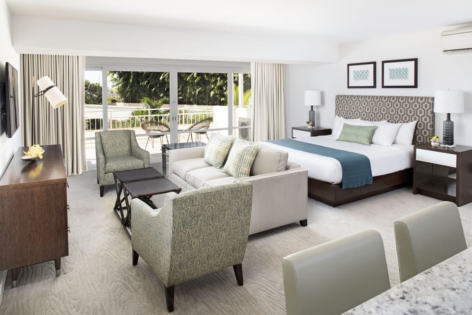 Your spacious suite blends comfort and style with plush bedding, a cozy sitting area, and a private balcony framing lush tropical greenery—perfect for unwinding after a day of adventure.