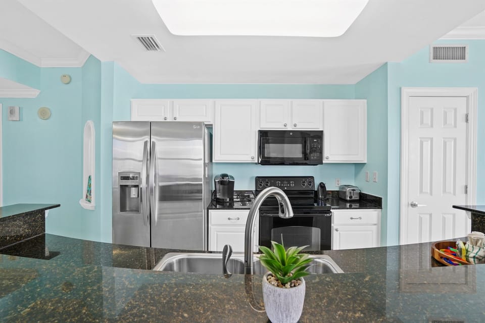Prepare delicious meals in your fully equipped kitchen featuring stainless steel appliances, granite countertops, and refreshing coastal-inspired decor.