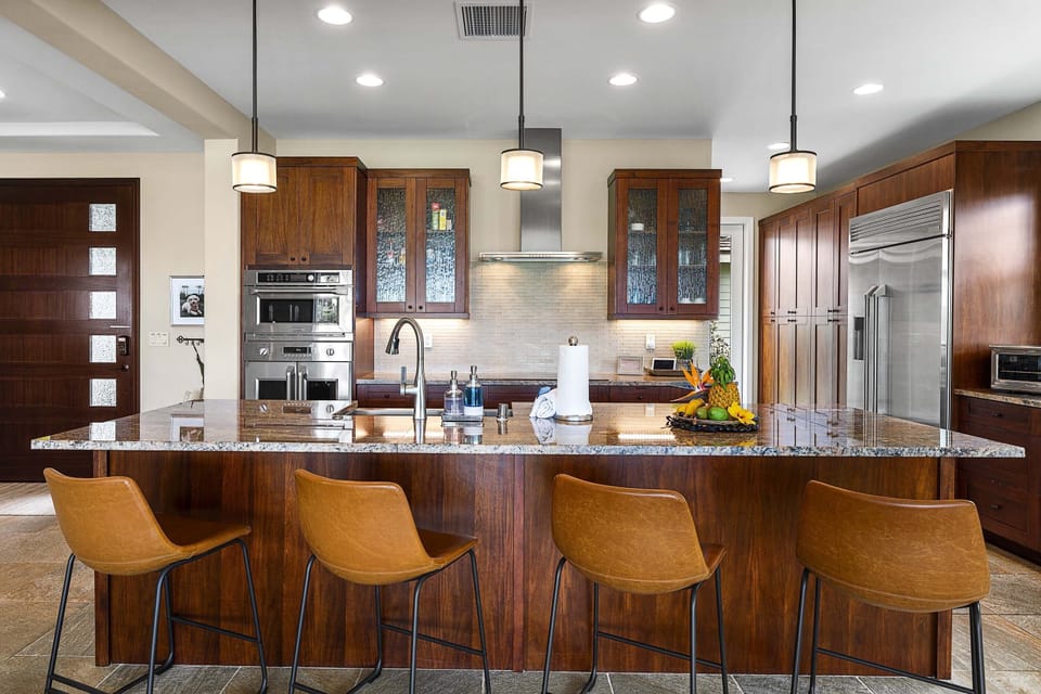 Pull up a seat at the breakfast bar in this gourmet kitchen featuring high-end finishes and custom lighting.
