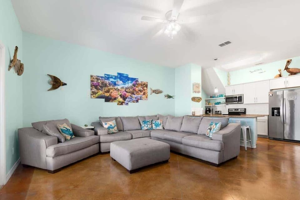 Living Room — Gray Sectional, Ottoman, Reef Canvas, Sea Pillows, Driftwood Fish & Turtle Art