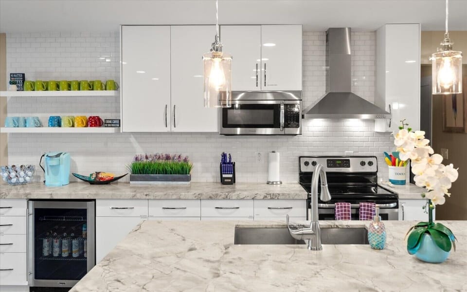Channel your inner chef in this sleek white kitchen equipped with high-end appliances and a built-in wine fridge.