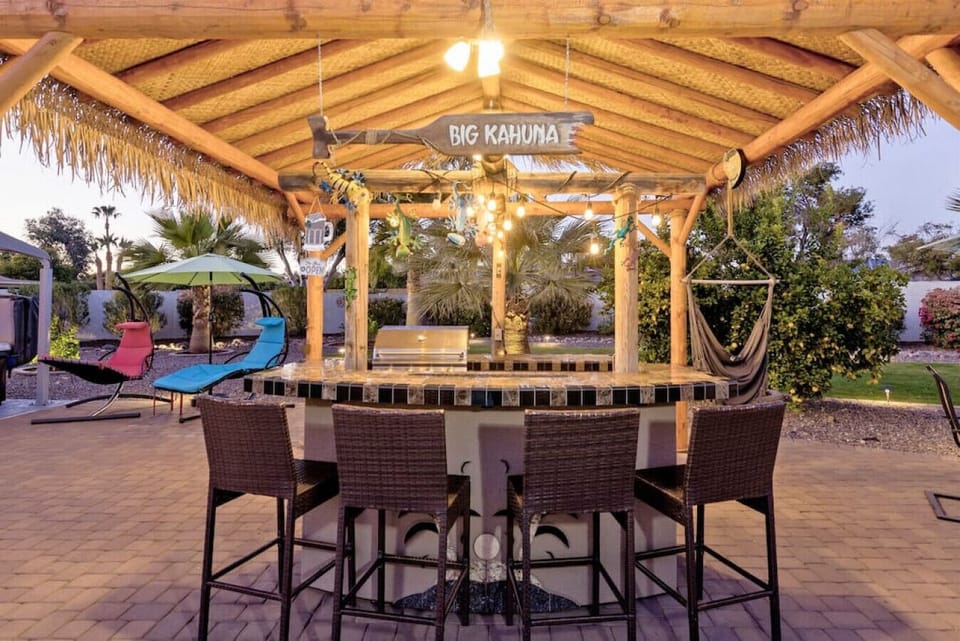 Covered outdoor bar with ambient lighting, seating, and tropical vibes for entertaining day or night.