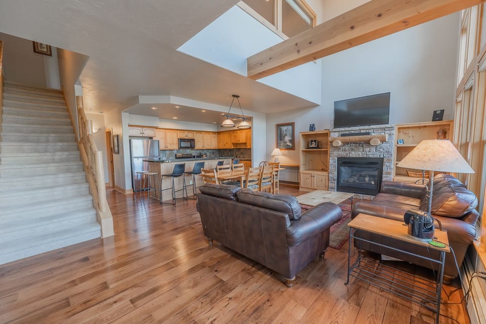 TV in living room with fireplace and large dining table.
