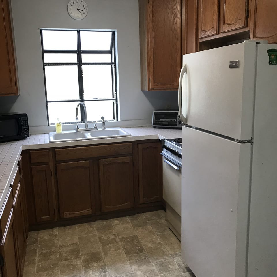 Kitchen features refrigerator, oven/range, microwave, and basic cooking items. 