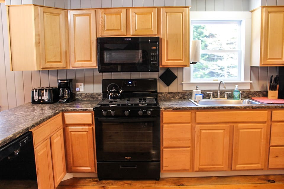 Fully stocked kitchen with cooking ware, utensils, plates and cups
