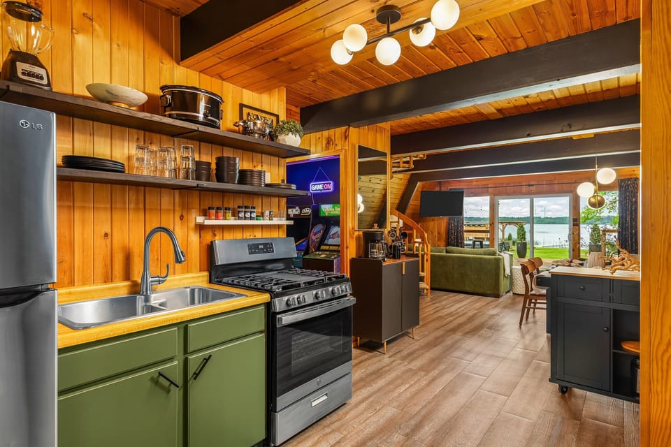 Cook, connect, and kick back—this open-concept kitchen flows into lake views, arcade fun, and cozy cabin comfort.