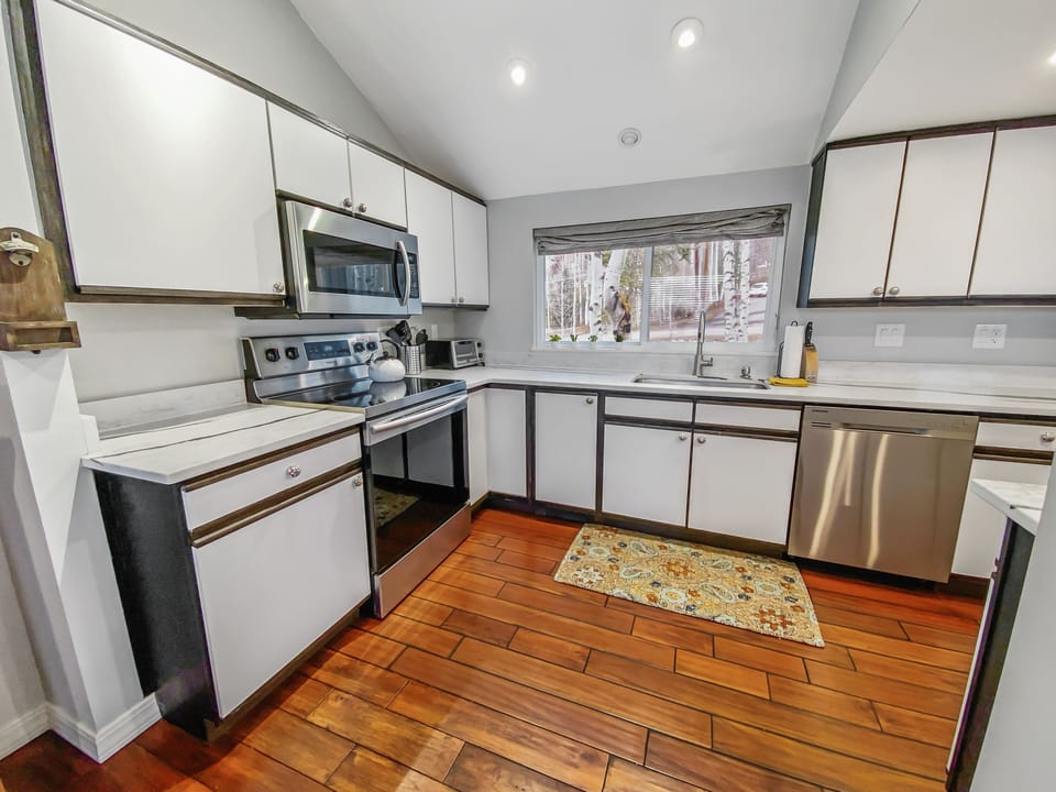Kitchen is equipped with electric range, microwave and dishwasher. 
