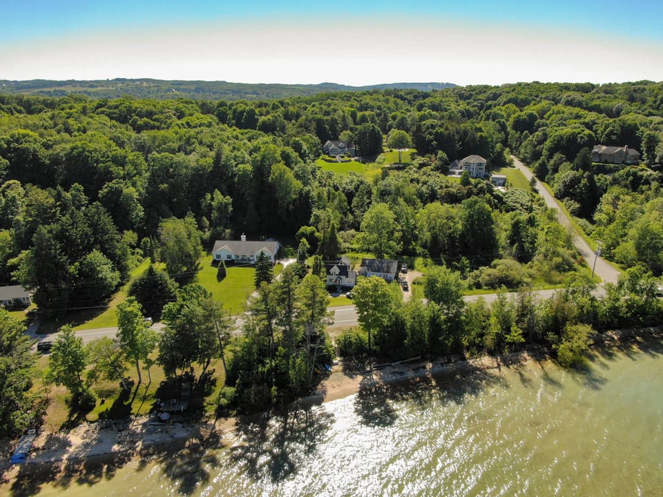 Sweeping aerial of the wooded shoreline & tranquil waters surrounding the home.