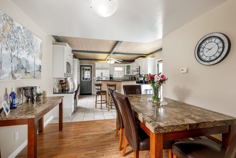 Open dining area w/ granite table & island seating, flowing seamlessly into the airy living space.