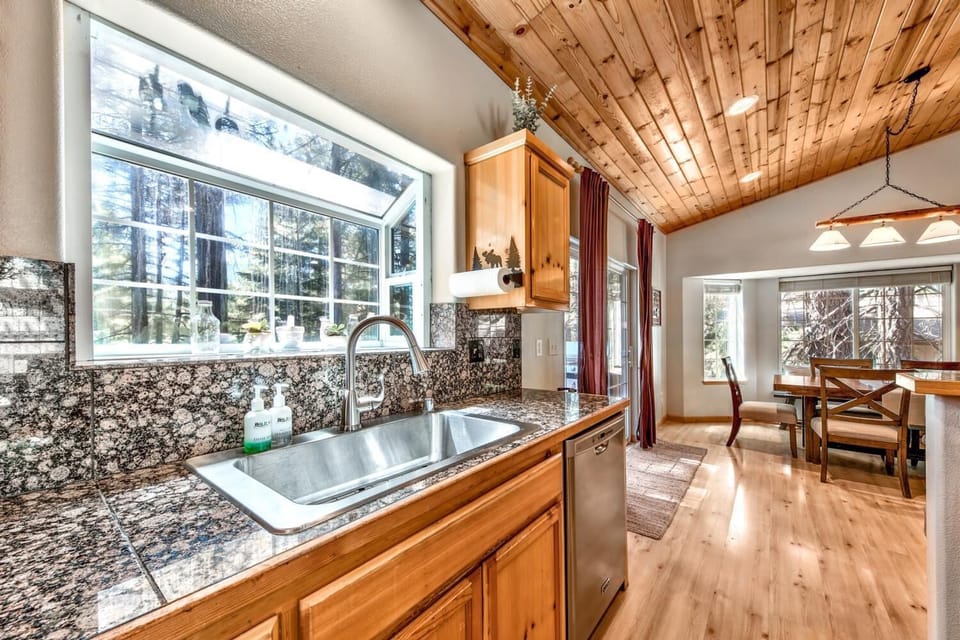 Your fully equipped kitchen features granite counters and forest views, perfect for preparing meals while staying connected to nature's beauty.