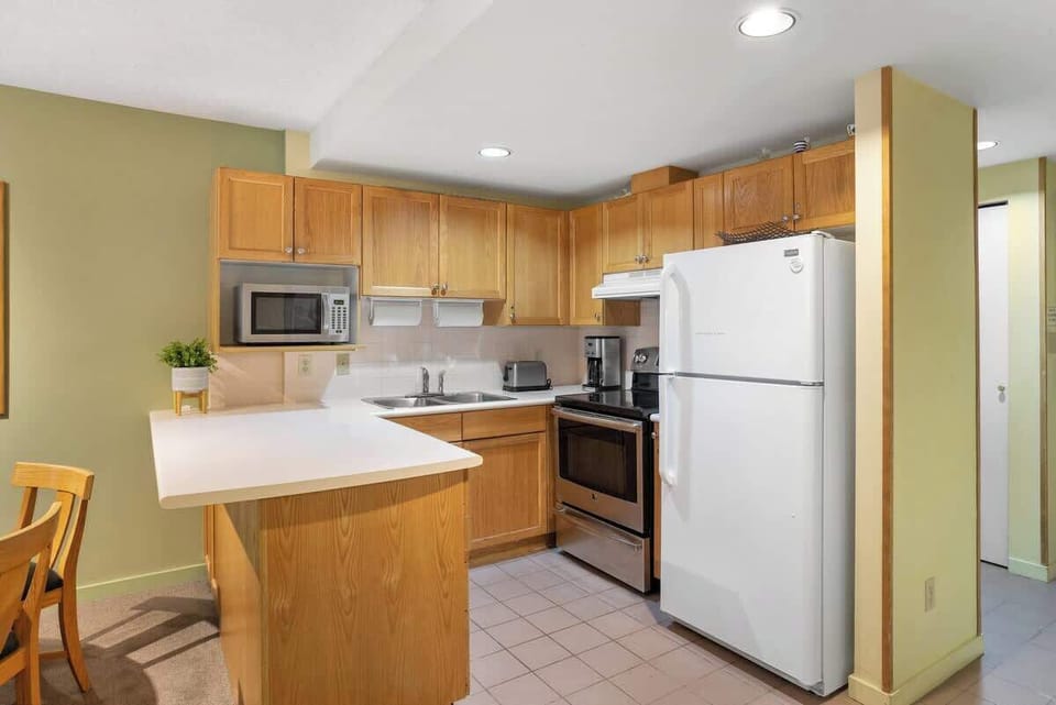 - Fully equipped kitchen with stainless appliances and warm wooden cabinets  
- Cook family meals in comfort after skiing or mountain biking  
- Whistler condo offering convenience and home-like luxury  