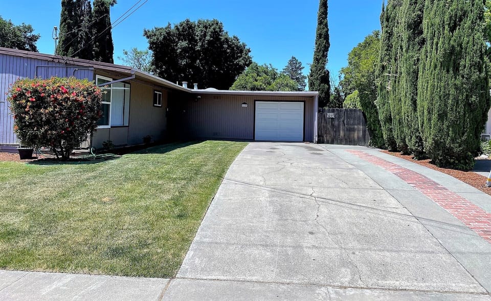 Entrance with cypress tress and large front lawn.