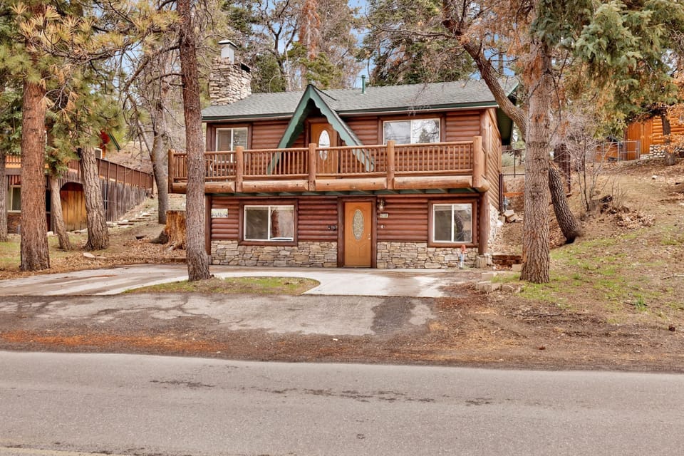 Welcoming cabin entry surrounded by towering pine trees, offering fresh mountain air and a peaceful forest setting—the perfect first impression for your Big Bear Lake getaway.