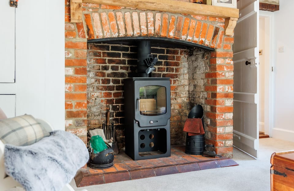 The traditional inglenook fireplace with its ornamental multi-fuel log burner creates a cosy focal point in the characterful living room at 1 Apse Castle Cottages. A warm and inviting space to relax after exploring Shanklin and enjoy your summer holidays on the Isle of Wight.