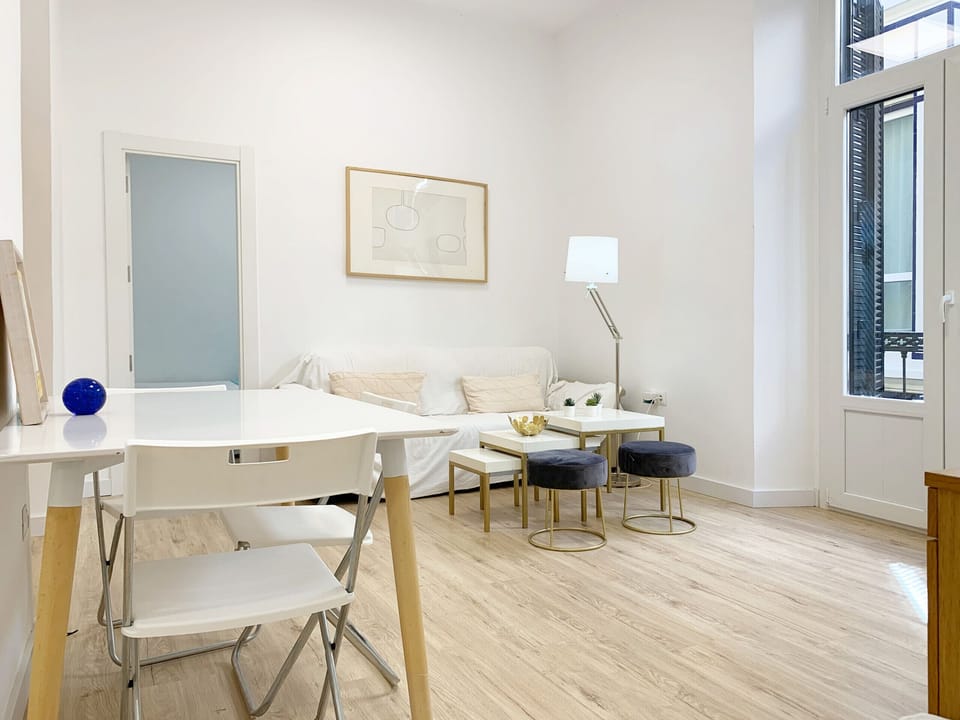 Well-lit living-dining room with air conditioner and sofa bed