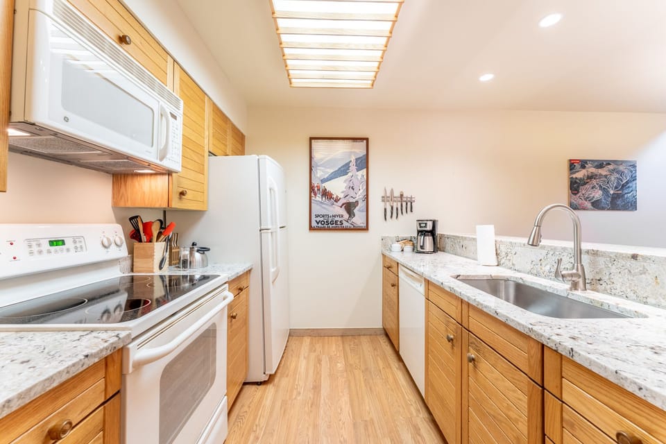 Cook with ease in your bright, well-equipped kitchen featuring granite counters, modern appliances, and a charming skylight overhead.