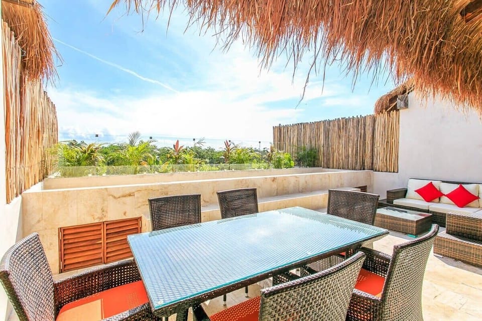 Outdoor dining area with woven furniture and tropical thatched roof.