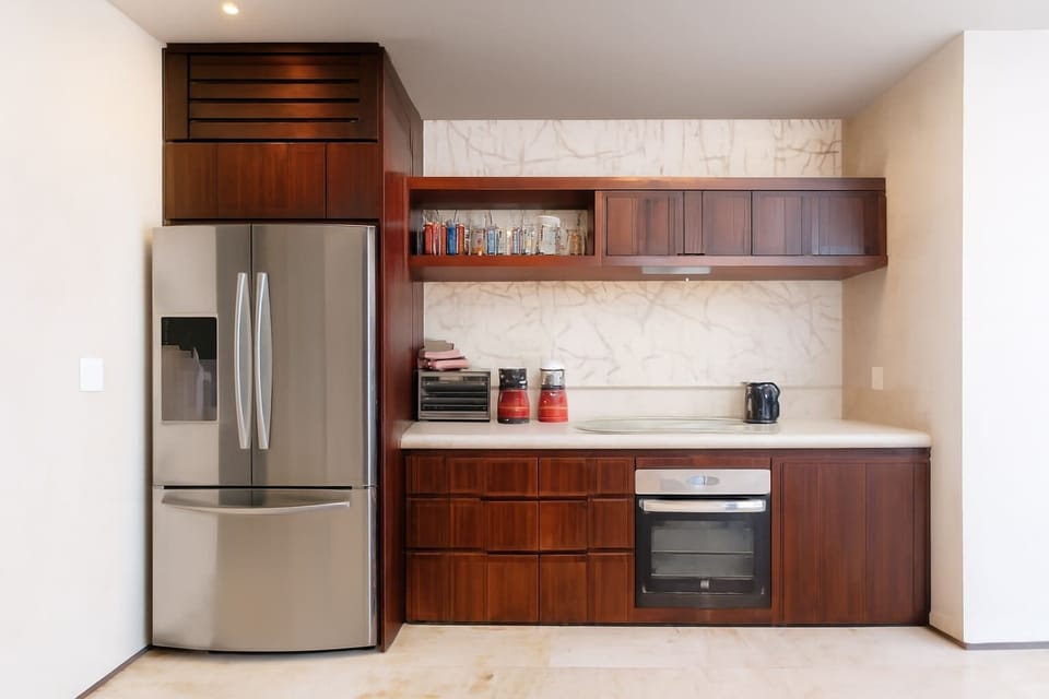 Modern kitchen with stainless steel refrigerator and dark wood cabinetry.