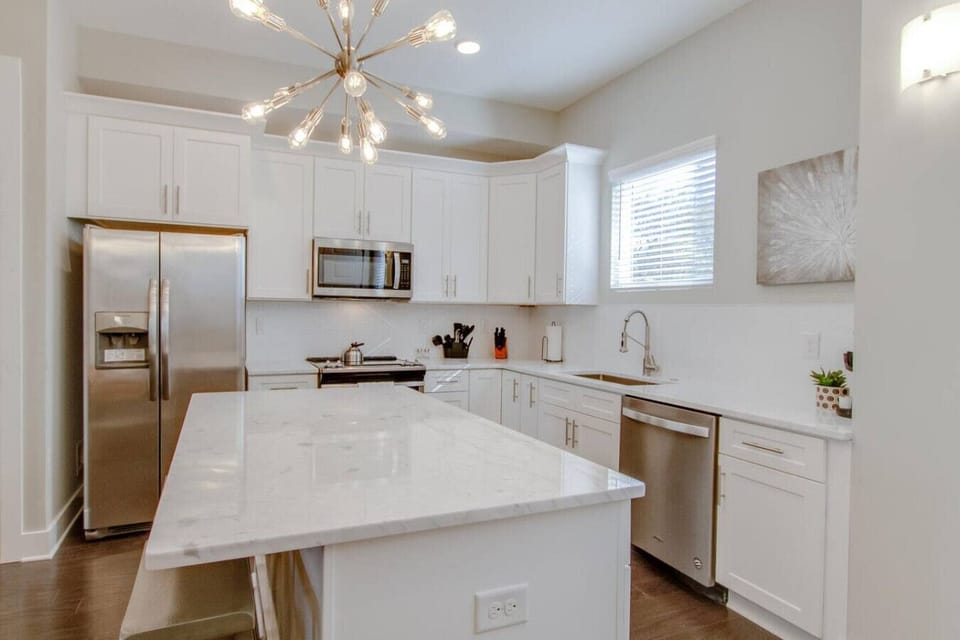 Sleek white kitchen with stainless steel appliances and a quartz island