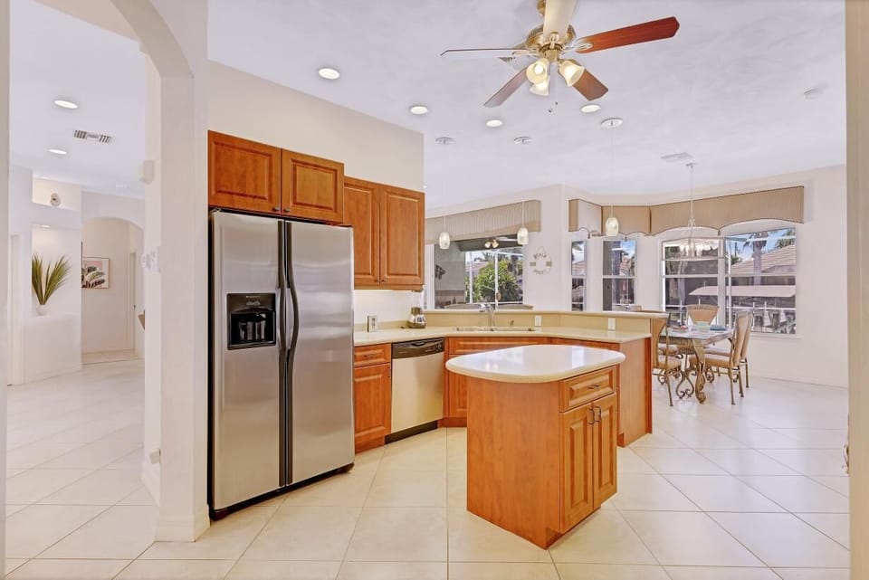 The open plan Kitchen with stainless steel appliances, wooden cabinetry + central island