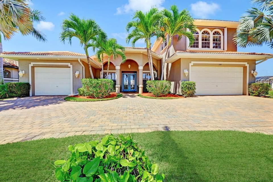 The front of the home with circular driveway and lush landscaping