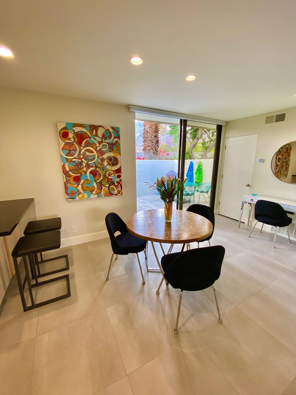 Dining area with vintage table, Jonathan Adler desk, and bright sliders