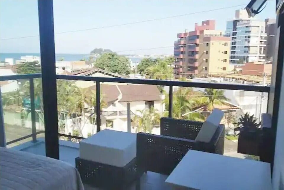Suíte com ar-cond, smart tv, ventilador de teto e sacada com vista para o mar.