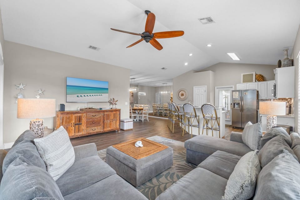 Bright open living area with vaulted ceilings, big sectional, and kitchen bar seating